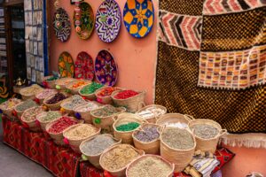 Colorful spices in baskets displayed with vibrant textiles in a market setting.