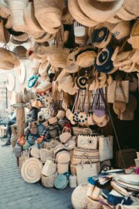 Vibrant display of handmade woven bags and hats in a Marrakesh street market.