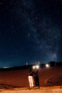 A couple under a stunning starry night sky in Agafay Desert, Morocco, embracing the beauty of nature.