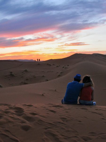 pexels-photo-12378898-12378898 A couple sitting together, embracing the stunning sunset in the Moroccan desert dunes.
