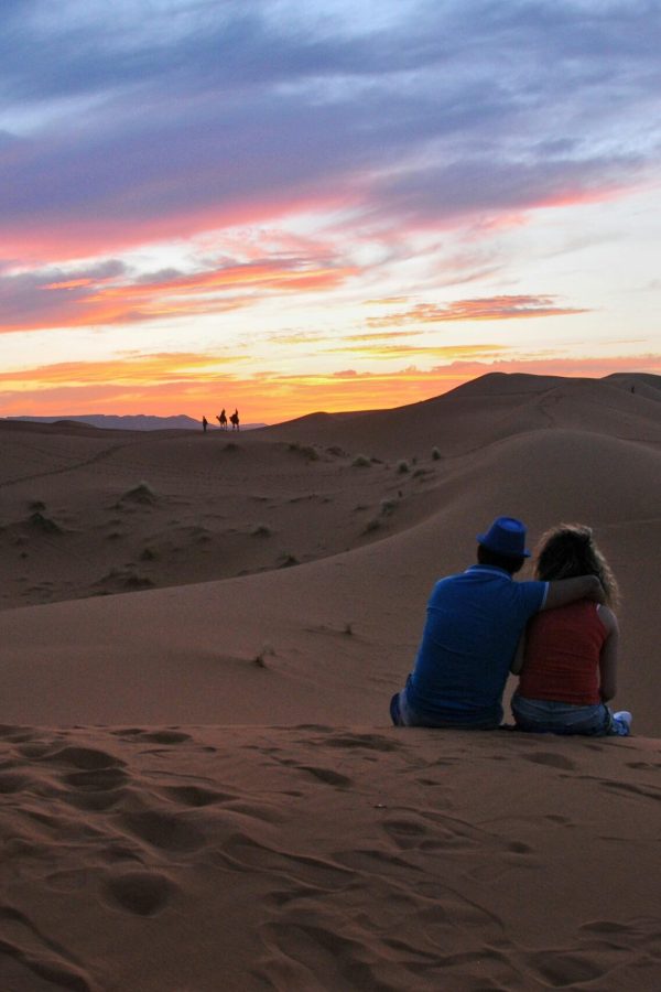 pexels-photo-12378898-12378898 A couple sitting together, embracing the stunning sunset in the Moroccan desert dunes.