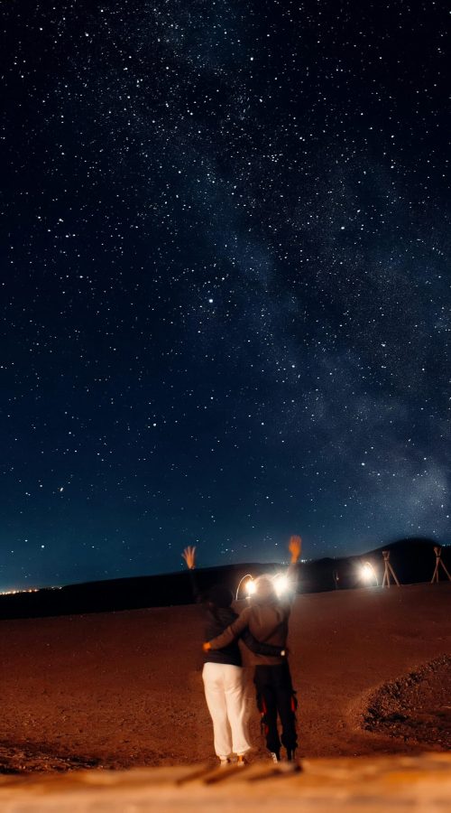 pexels-photo-15257194-15257194 A couple under a stunning starry night sky in Agafay Desert, Morocco, embracing the beauty of nature.