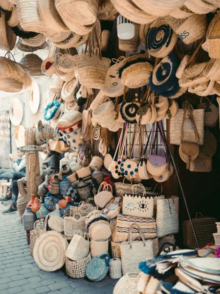 Vibrant display of handmade woven bags and hats in a Marrakesh street market.