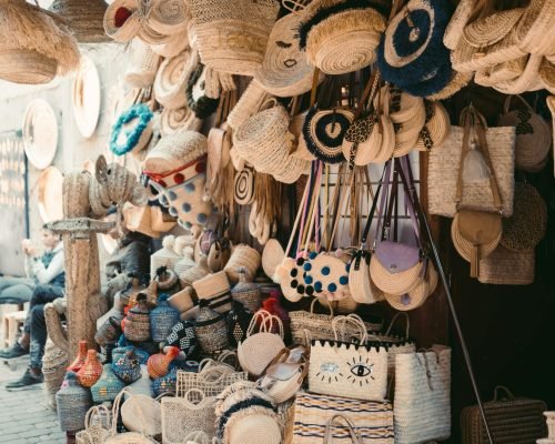 Vibrant display of handmade woven bags and hats in a Marrakesh street market.